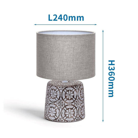 Dekorative Tischlampe aus Keramik mit Ornamenten und rundem Stoffschirm.