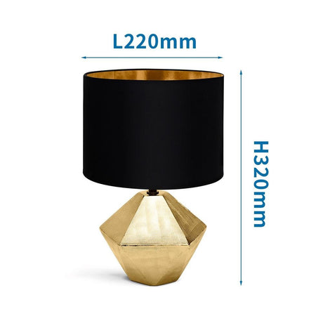 Edle goldfarbene Tischlampe aus Keramik mit 6-eckigem Fuss und schwarzem Stoffschirm.